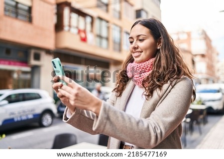 Young beautiful hispanic woman make selfie by smartphone wearing scarf at street