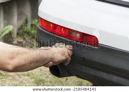 Scratched rear bumper on a white car, cracks and bumper repair close-up. White car with a broken and cracked bumper Royalty-Free Stock Photo #2185484141