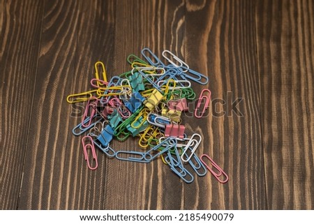 stationery colored paper clips on a wooden background, the concept is coming to school soon