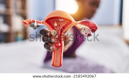 African american woman holding anatomical model of fallopian tube at bedroom Royalty-Free Stock Photo #2185492067