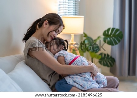 Asian beautiful mother hug sleeping baby girl in her arms with gently. Loving young parent holding small baby to rest on shoulder and sleep with young daughter. Parenting relationship at home concept. Royalty-Free Stock Photo #2185496625