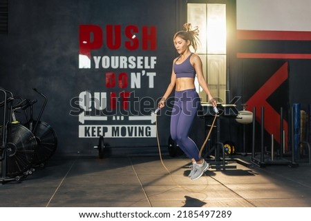 Asian athlete woman workout to maintain muscle in fitness gym club. Attractive young sportsfemale exercising by using jumping rope to burns calories and strengthens body for health care in stadium. Royalty-Free Stock Photo #2185497289