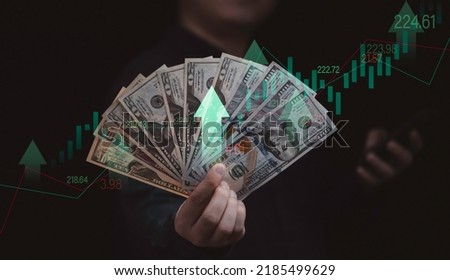 Businessman holding dollar banknote with stock market graph and up arrow for inflation and interest rating increasing concept. Royalty-Free Stock Photo #2185499629
