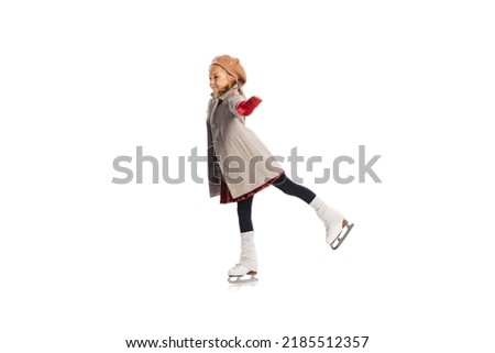 Portrait of stylish little girl, child posing, skating isolated over white studio background. Winter holidays. Concept of childhood, friendship, fun, lifestyle, fashion. Retro style