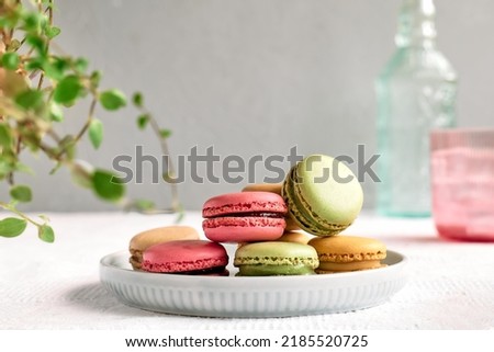 Colorful french macarons on pastel background. Tasty cake macaroon of different colors in the plate. Almond cookies, pastel colors.