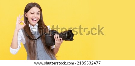 cheerful kid girl take photo with digicam show ok gesture, photography. Child photographer with camera, horizontal poster, banner with copy space. Royalty-Free Stock Photo #2185532477