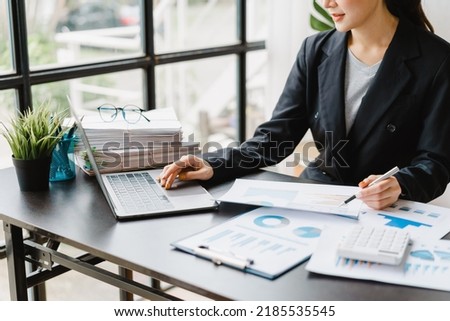 Young pretty business woman Asian people working with laptop in modern office workplace with paper chart and graph.
