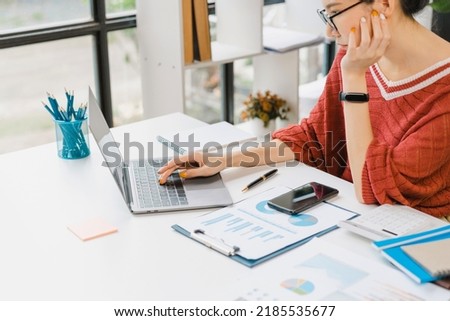 Bored asian nerd lady working with laptop computer when sitting at desk.