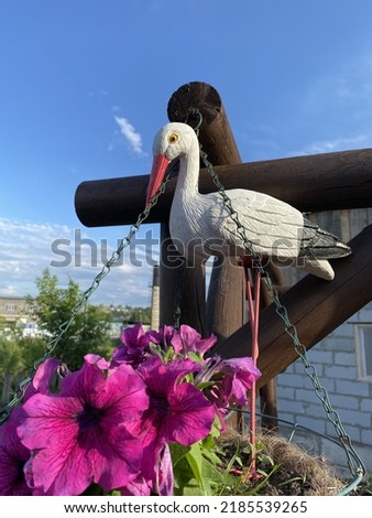 stork statue with pink petunia selective focus