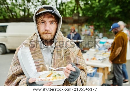 Homeless man eating food outdoors Royalty-Free Stock Photo #2185545177