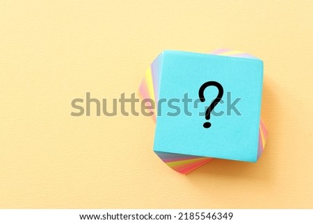 Top view image of sticky note and question mark over textured paper