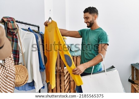 Young arab man customer smiling confident shopping at clothing store Royalty-Free Stock Photo #2185565375