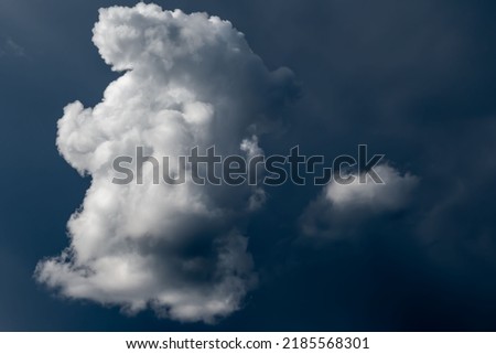A white cumulus cloud against a dark sky. Background picture.