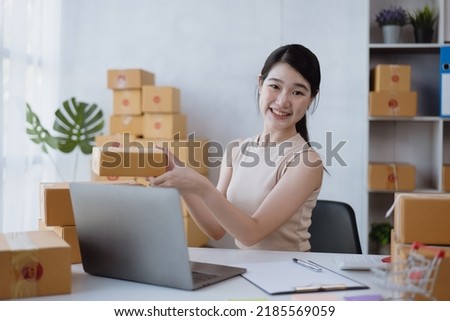 Young owner business woman live broadcast streaming for selling the products in parcel cardboard box packaging via laptop.