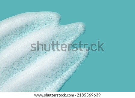 Foam lather texture background. White cleanser gel, shaving foam, shampoo bubbles on blue.