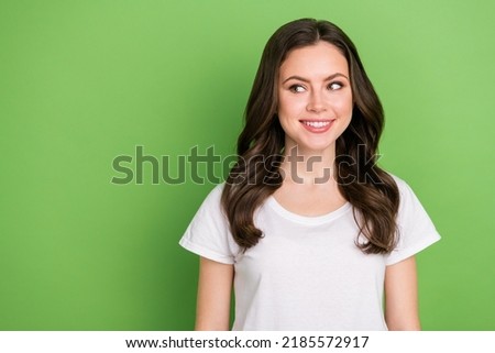 Photo of dreamy pretty young lady wear white t-shirt smiling looking empty space isolated green color background