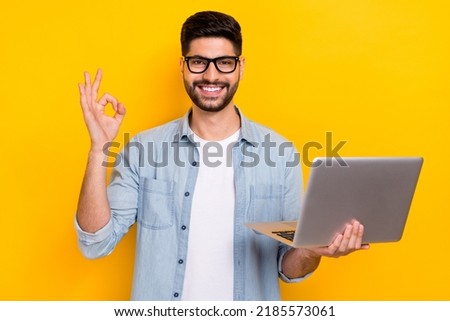 Photo of young business guy holding laptop showing okey sign buy advertisement google happy isolated on yellow color background