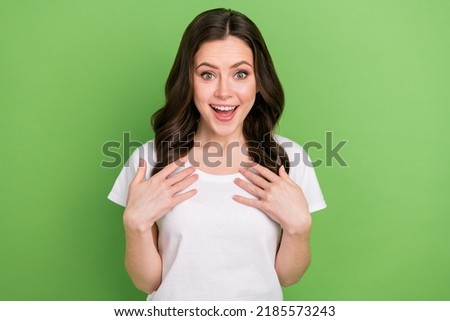 Photo of impressed funky young lady wear white t-shirt arms chest smiling isolated green color background