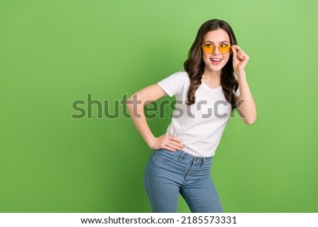 Photo of adorable pretty young lady wear white t-shirt arms dark glasses looking empty space isolated green color background