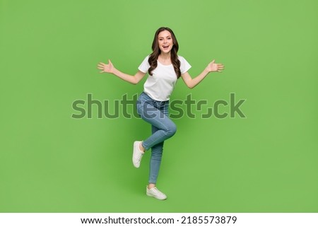 Photo of impressed funky young lady wear white t-shirt smiling dancing isolated green color background