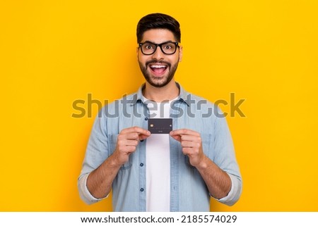 Photo of young guy wear denim shirt happy buy shopping sales holding credit card isolated on yellow color background