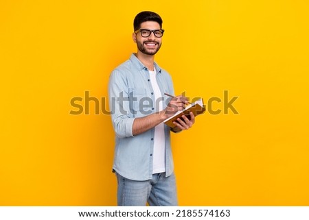 Photo of handsome hispanic guy hold notepad create business plan wear trendy denim garment spectacles isolated on yellow color background