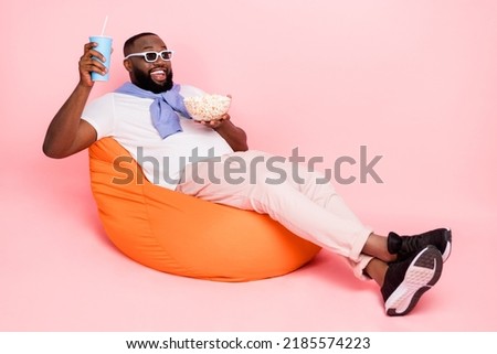 Full size photo young cheery guy watching 3d movie in theater sitting comfy armchair isolated on pink color background