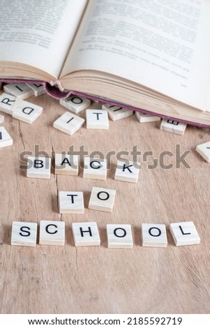 school, back to school concept photo with cube letters and opened book on wooden table or background or surface. education concept template photo with selective focus