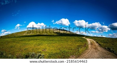 The road through the field to the hill. Hill road panoramic landscape. Summer hill road. Hill road panorama Royalty-Free Stock Photo #2185614463