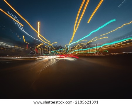 Abstract light trails of the night rush drive on the highway. Front view from the car window to the road and headlights of other vehicles in movement.