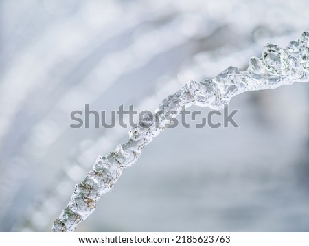 Splashes of water against light background. Fountain, a jet of water against cloudy sky.