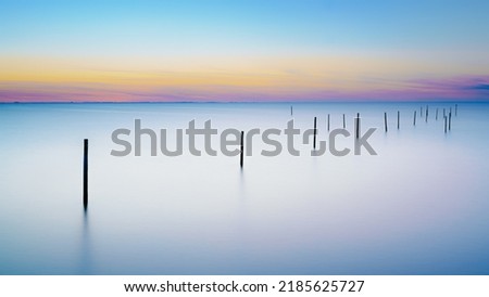 Long exposure picture of a fyke at the IJsselmeer with the endless horizon during an atmospheric sunset in spring