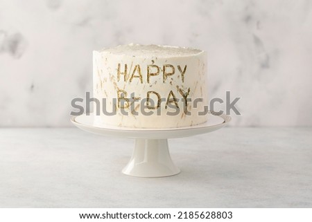 White birthday cake on a cake stand on white background. Simple minimalism.