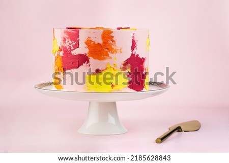 Rainbow cake with whipped cream top on the pink background. Birthday cake with multicolored cream cheese frosting. 