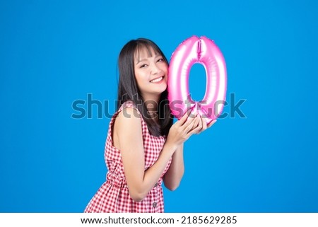 Happy new year and Merry Christmas concept. Beautiful young asian woman with balloons number 0 on blue background.