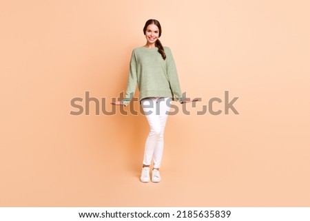 Full length photo of sweet adorable girl dressed green pullover smiling isolated beige color background