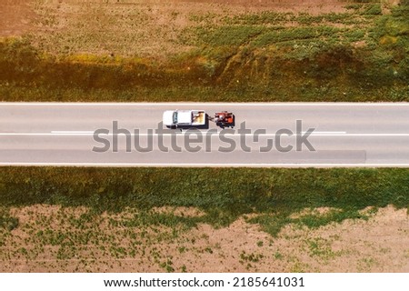 Aerial shot of pickup truck with trailer on highway through countryside landscape, drone pov directly above