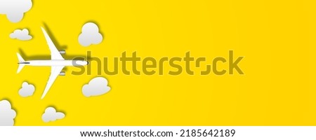 Flat lay or table top picture of aircraft with clouds as paper cut outs. Airplane is to illustrate travel background. Picture has copy space, deign for mock up. yellow background