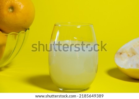 yellow grapefruit in glass fruit bowl on yellow table, glass of milk