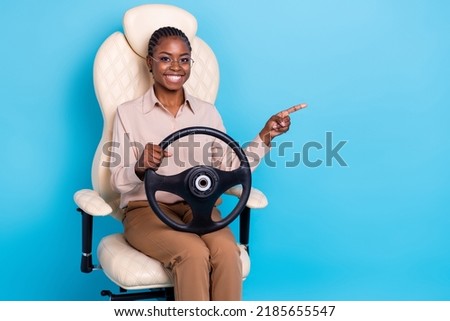 Photo of cheerful beautiful young female promote advertise driving school sit chair isolated on blue color background