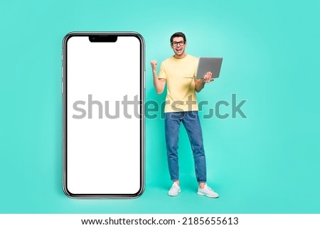 Full body photo of hooray brunet guy hold laptop index promo wear eyewear t-shirt jeans sneakers isolated on teal background