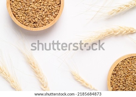 Whole wheat grain in wooden bowl on white background, food ingredients, Top view