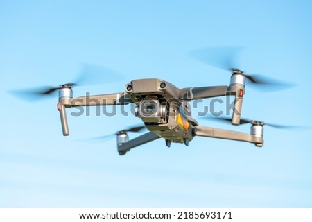 A modern quadrocopter soars in the air against a blue sky, a drone