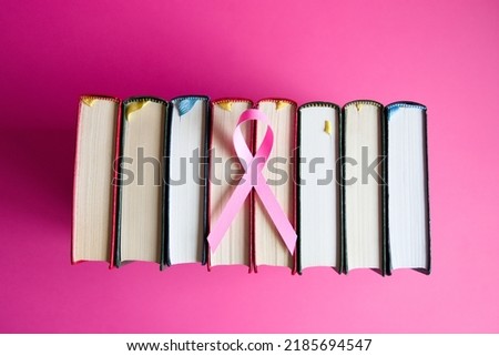 A bird's-eye view of a pink background with a pink ribbon and books arranged side by side