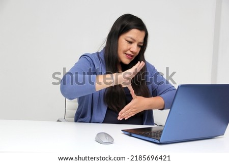 Latino adult woman speaks Mexican sign language with a deaf person through a laptop in a video call
