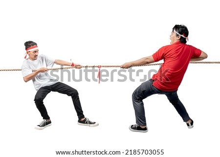 Two Indonesian men celebrate Indonesian independence day on 17 August with the tug of war contest isolated over white background Royalty-Free Stock Photo #2185703055