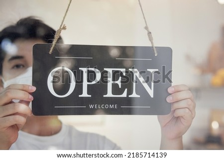 Store owner turns open sign broad through the door glass and ready to service for customers. opening of the cafe or shop 