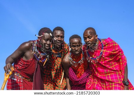 Maasai Mara man in traditional colorful clothing showing traditional Maasai jumping dance at Maasai Mara tribe village famous Safari travel destination near Maasai Mara National Reserve Kenya Royalty-Free Stock Photo #2185720303