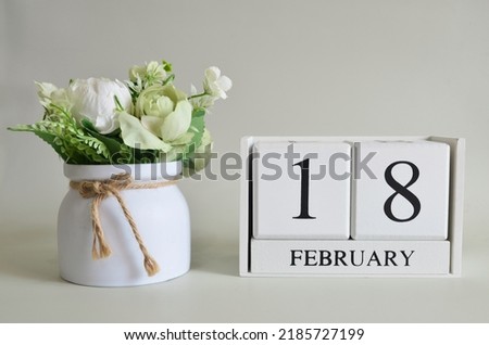 February 18, Cover natural background, white wooden Calendar cube with a pot flower on white background.