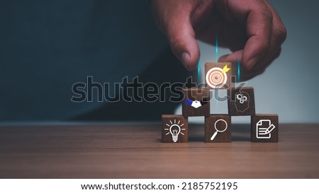 Business service concept to success . Businessman holding wooden block target board icon on wooden cube block with business strategy icon, business strategy planning. To winner business competition.